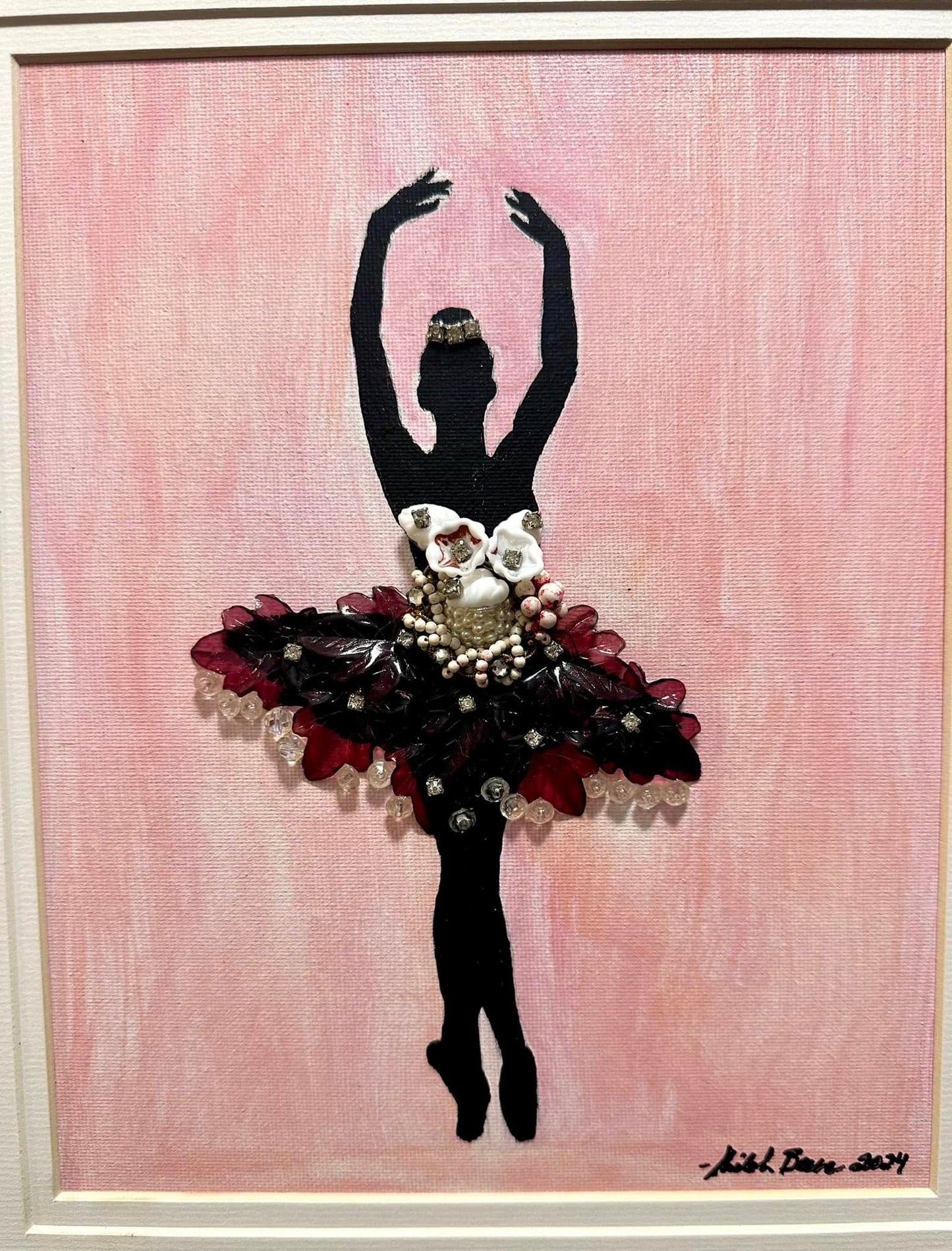 Artistic depiction of a ballerina silhouette with floral details made from vintage jewelry on a pink background in a golden frame