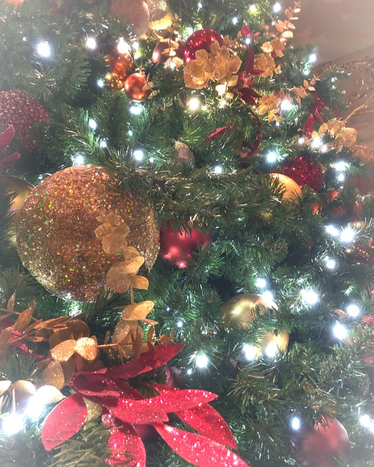 Decorated Christmas tree with lights, ornaments, and red and gold decorations.