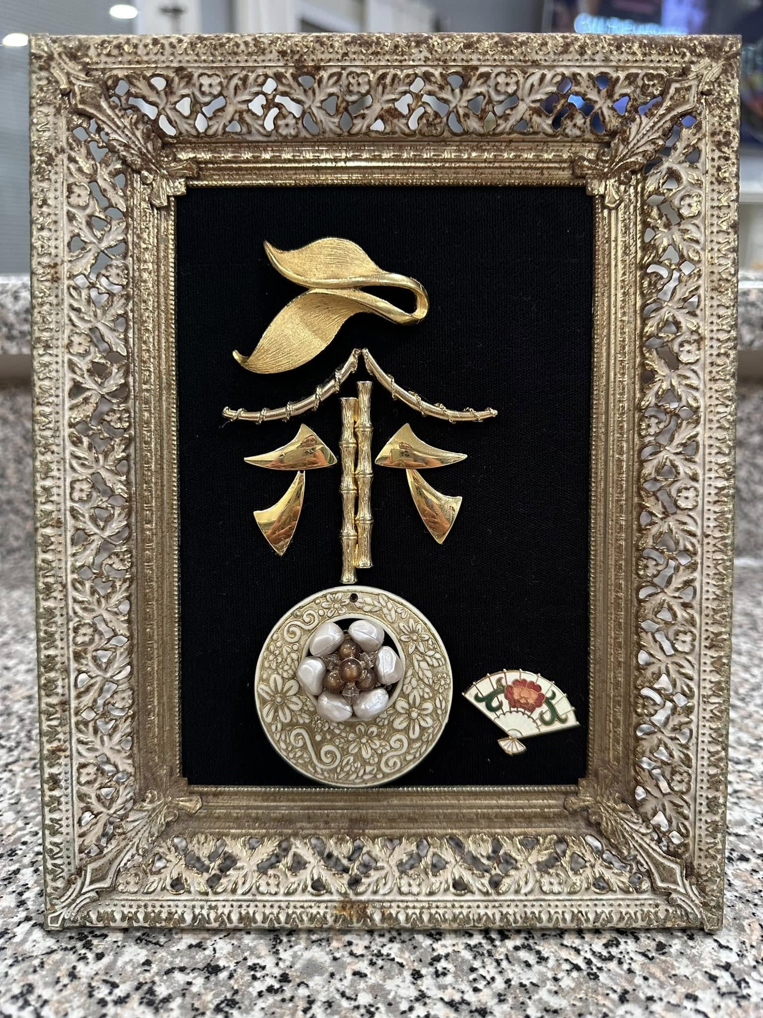 Art piece made of vintage jewelry on velvet, in an old decorative frame