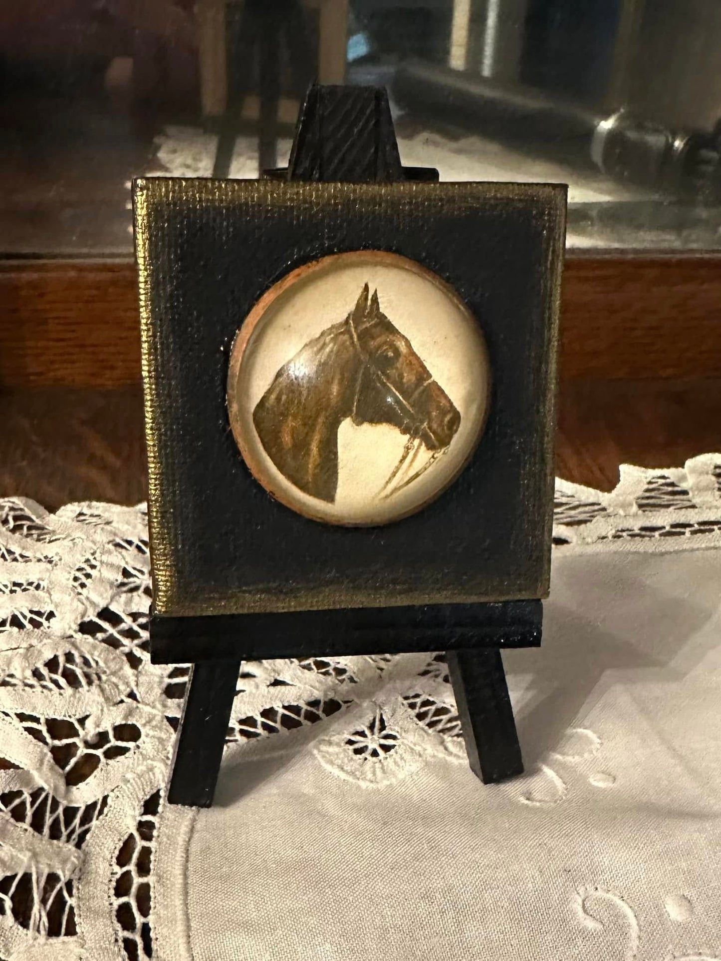 This exquisite horse brooch features intricate detailing on a 2.5" x 2.5" canvas, showcasing original artwork as its backdrop, and . presented on a mini-easel. It stands about 5" tall and is the perfect little piece of mini-art to bring color, beauty, fun, and joy to any space- an end table, kitchen or bathroom counter, shelf decor, work space, etc. It's a nice affordable gift for yourself, a family member, a friend, or coworker.